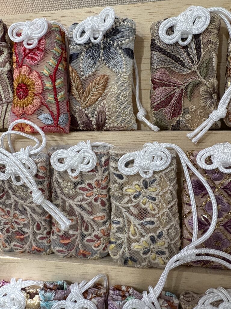 A variety of shrine charms, talismans, and protective amulets on display at Wakinohama Shrine, including traditional paper and cloth omamori.
