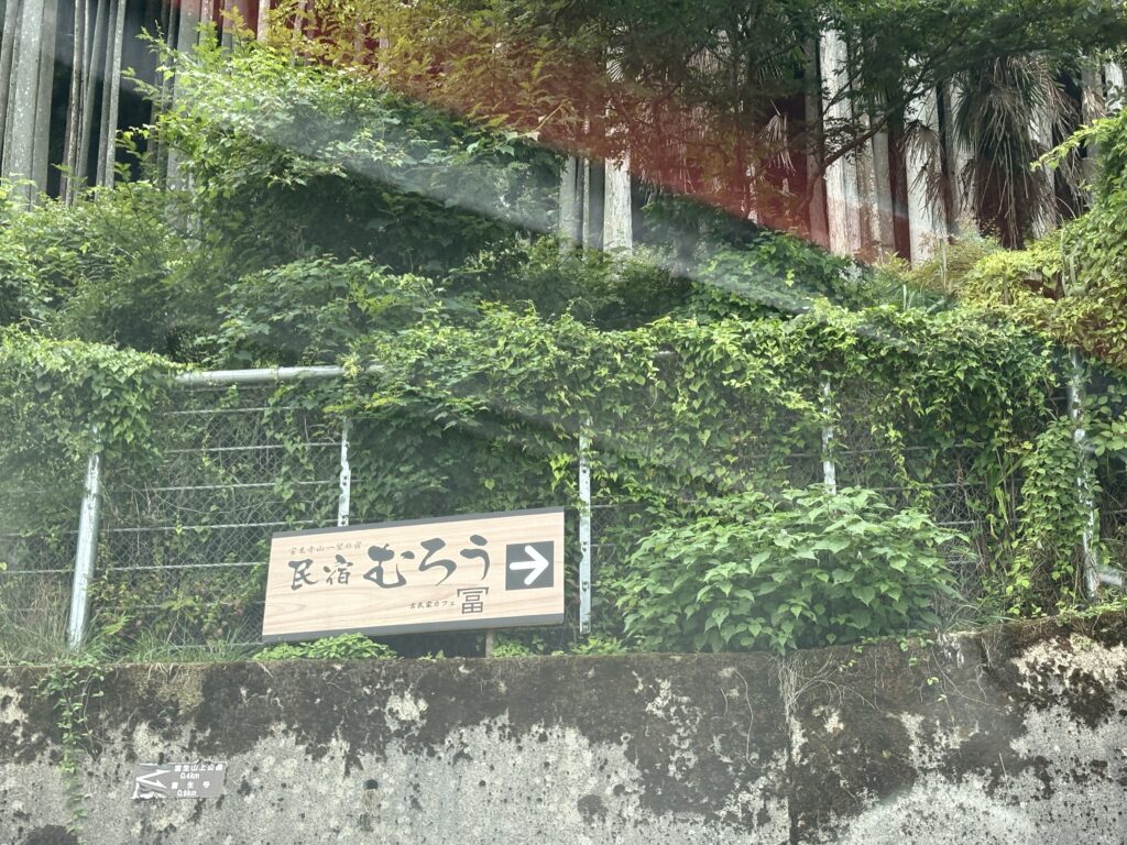 Wide view of Morou Art Forest with a circular stone pattern and sculptures against a forested mountain backdrop.