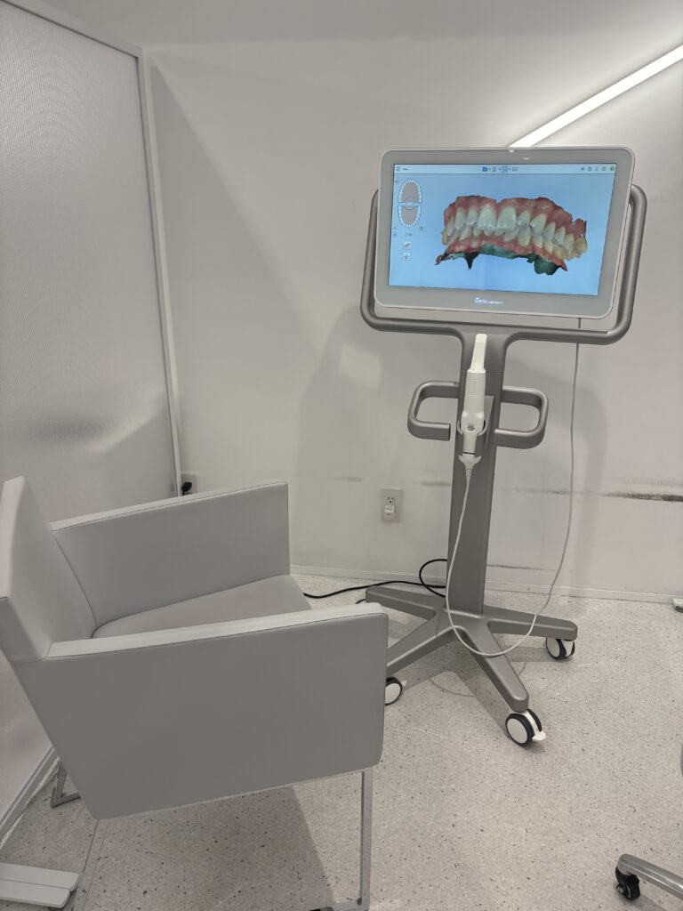 Modern dental scanning equipment displaying a 3D digital image of teeth on a monitor in a clean orthodontic clinic.