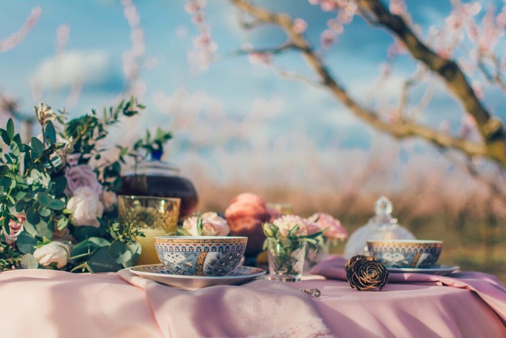 A blue and gold teacup set with cinnamon rolls and a strawberry cupcake.