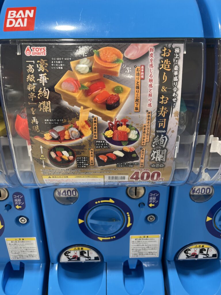 Capsule machine featuring realistic sushi toy replicas, including nigiri and sashimi pieces, detailed miniatures priced at 400 yen.