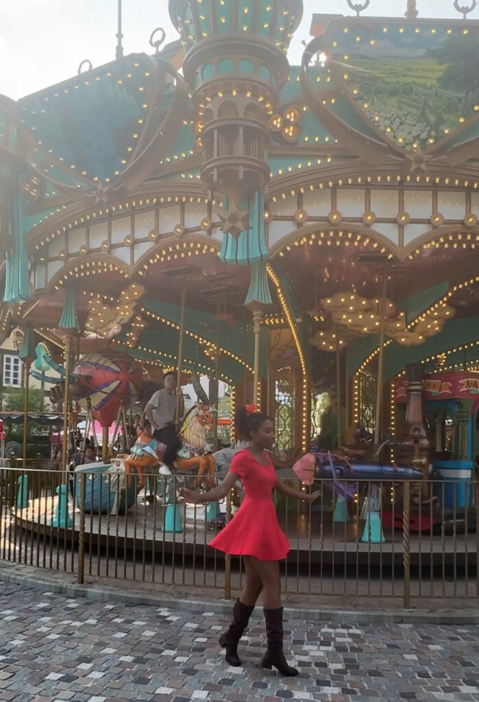 Howl’s-themed carousel in Valley of Witches with a woman in a red Kiki-style dress twirling in front.