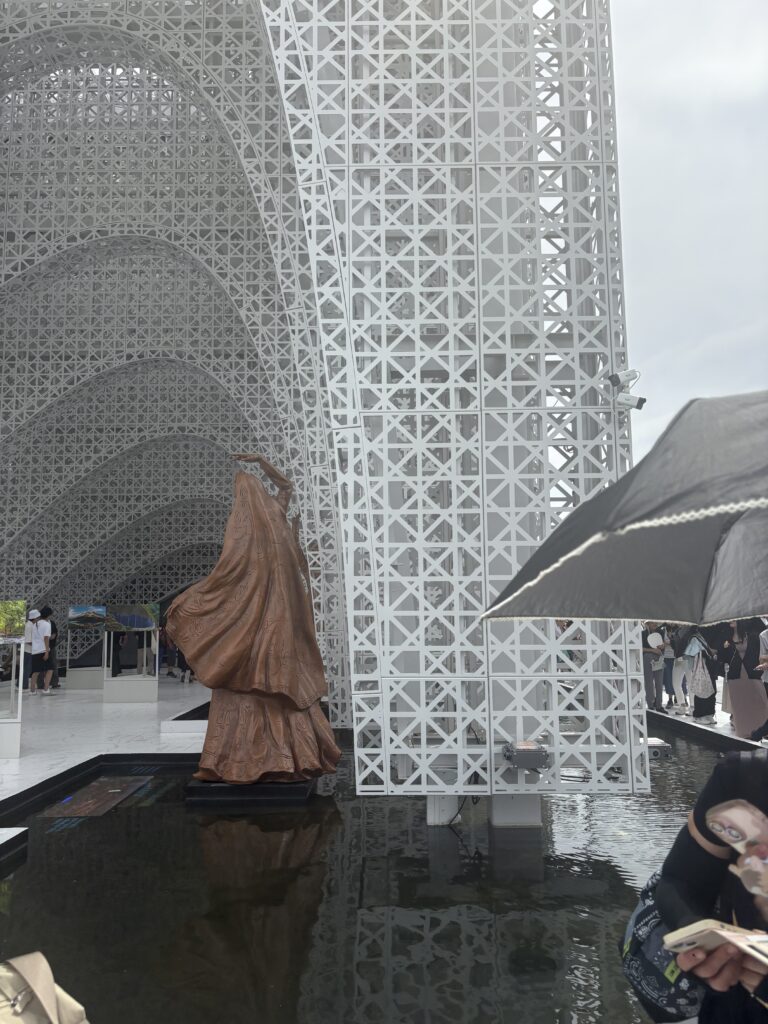 White lattice pavilion with wooden statue at Osaka Expo 2025