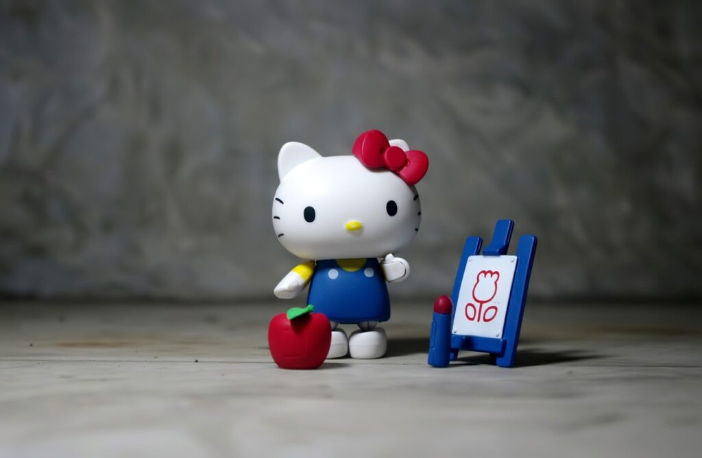 Hello Kitty figurine with red apple and easel.