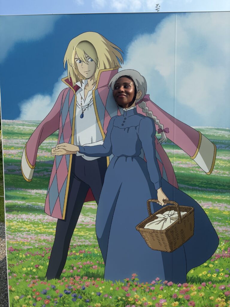 Visitor posing with her face in a cutout board of Howl and Sophie from Howl’s Moving Castle.