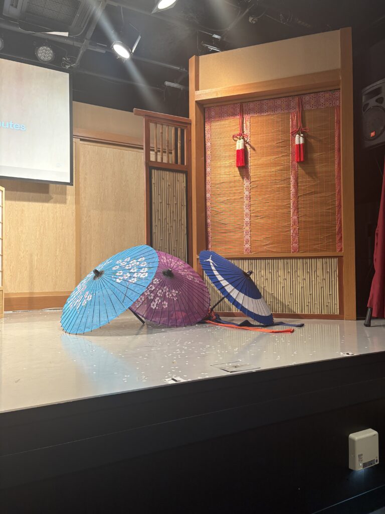 Brightly colored Japanese parasols (blue, purple, and striped) set on stage as props for the performance.