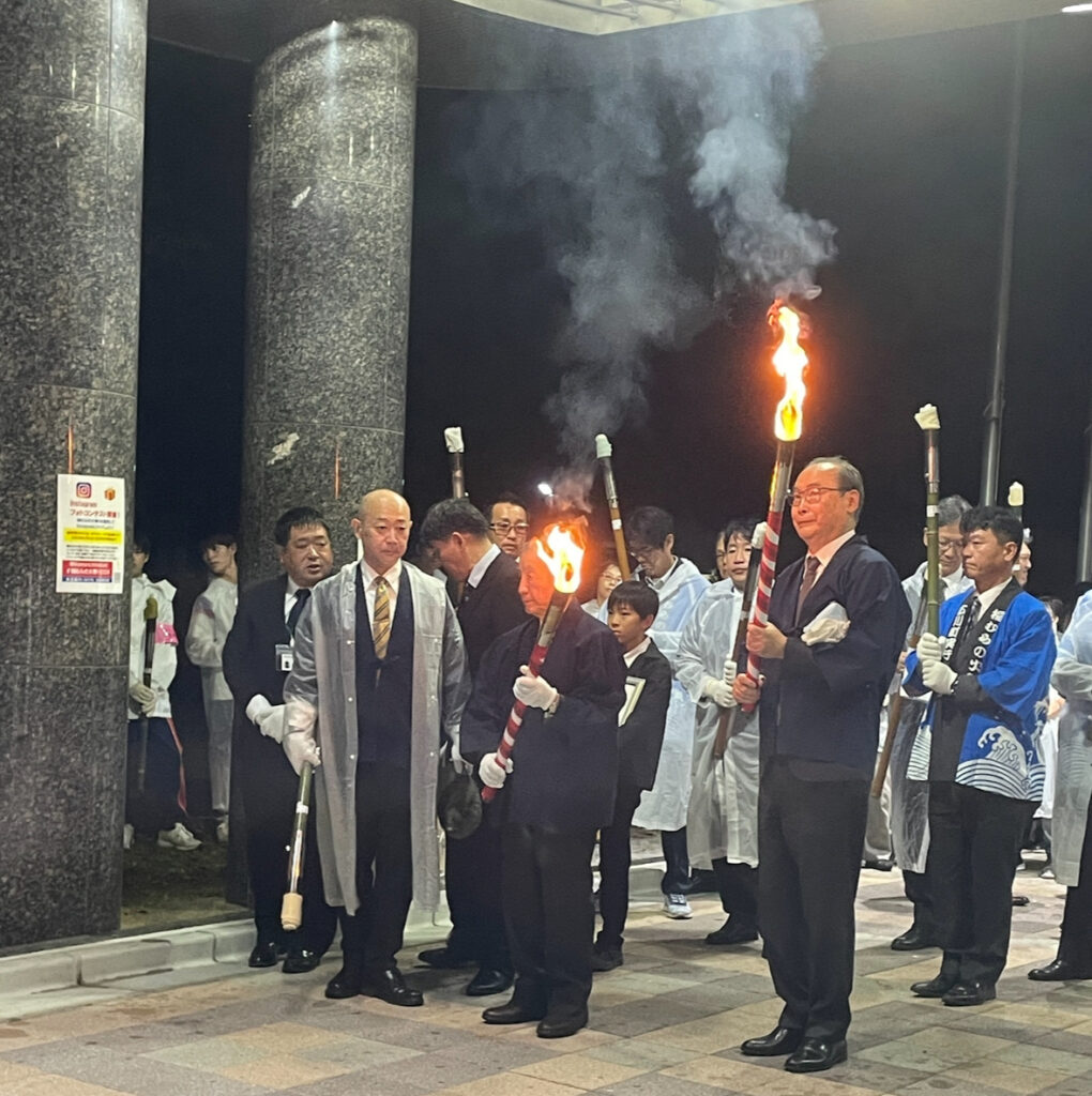 Group of participants holding fire torches before procession.
