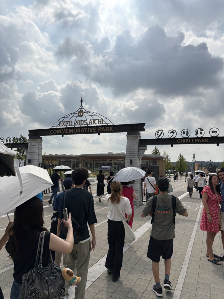 Expo 2005 Aichi Commemorative Park gate with “Ghibli Park” signage as visitors walk in.