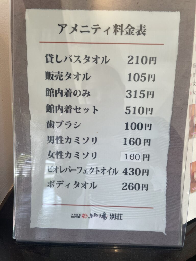 A signboard listing amenity rental prices at Kinu no Yu Villa, including towels, robes, razors, and bath items.