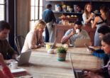 People working on laptops and drinking coffee inside a modern Tokyo café with communal tables.
