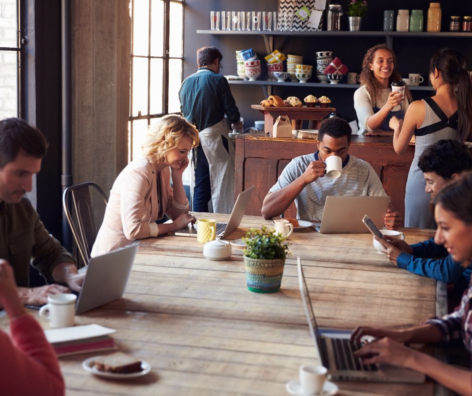 People working on laptops and drinking coffee inside a modern Tokyo café with communal tables.