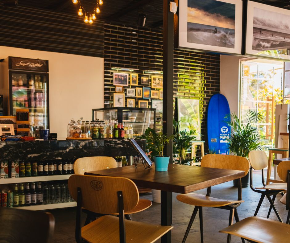 Interior of a cozy Tokyo café with surfboards, framed art, and wooden chairs.