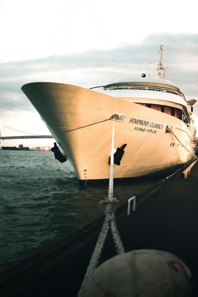 A large white cruise ship named Symphony Classica docked at Tokyo Bay, with Rainbow Bridge visible in the distance.