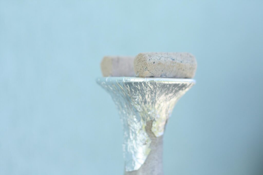 Close-up of a shisha bowl wrapped in foil with charcoal pieces on top.
