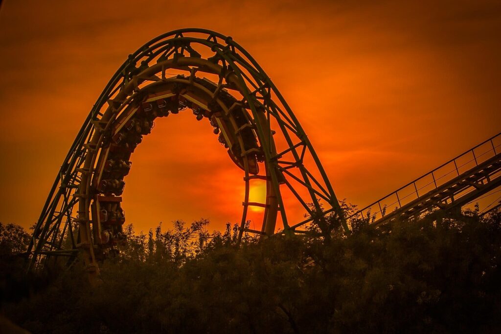 Roller coaster looping at sunset with an orange sky, creating a dramatic Halloween-like atmosphere.
