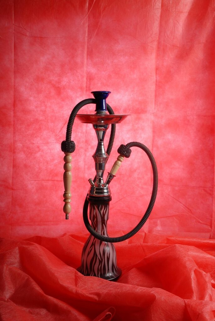 Decorative hookah pipe against a red background.