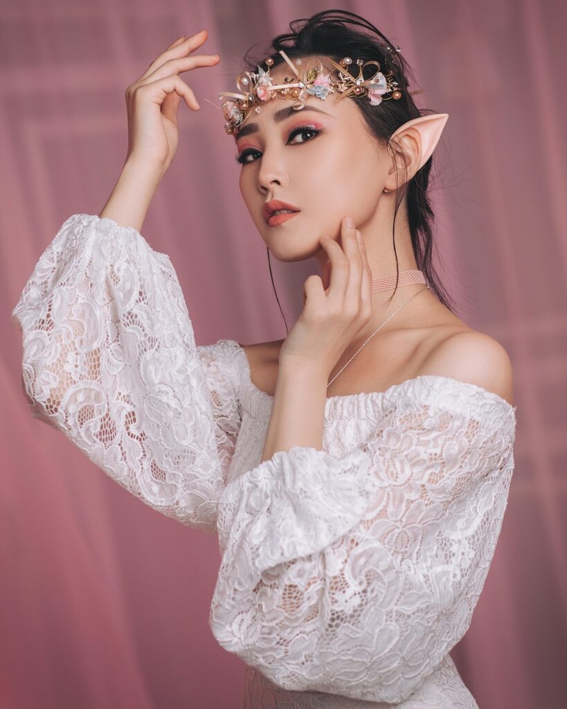 Woman in fantasy elf costume wearing a white lace dress and floral headpiece with pointed ears.