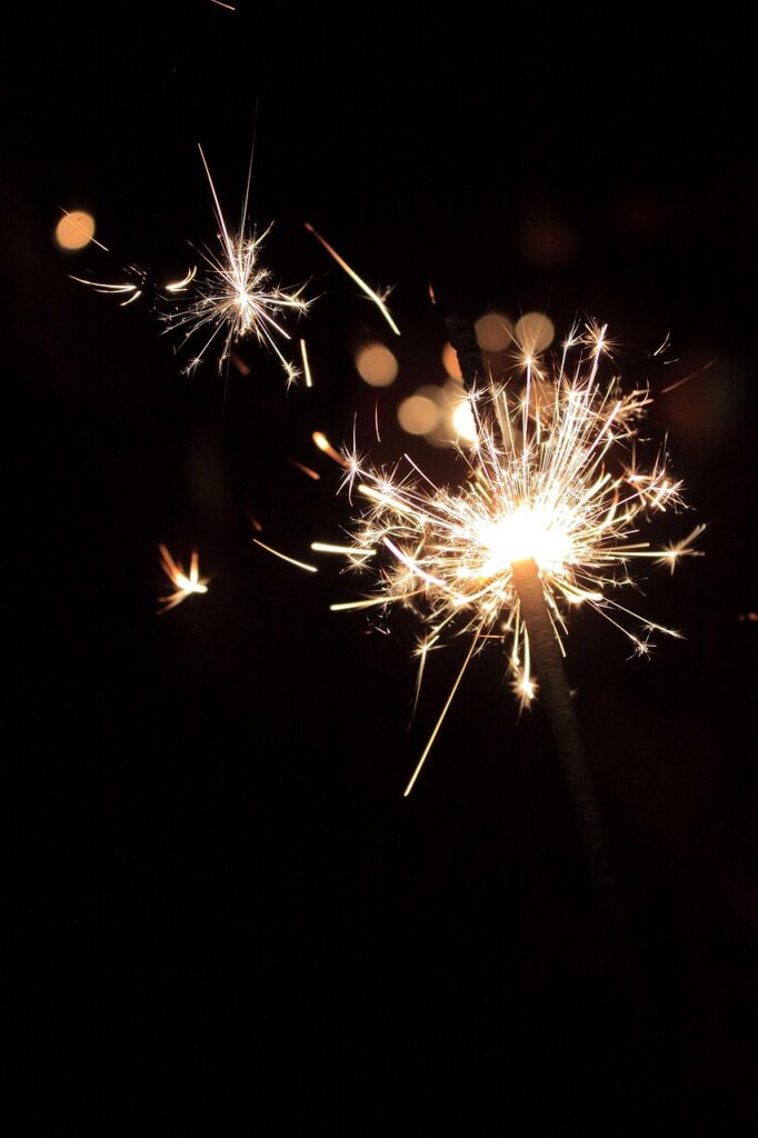 A handheld sparkler glowing brightly in the dark.