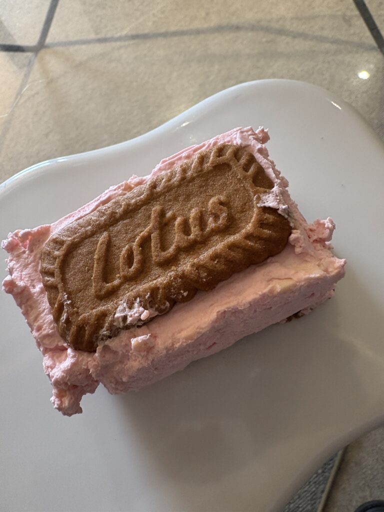 Pink Lotus Biscoff cake slice on a white plate.
