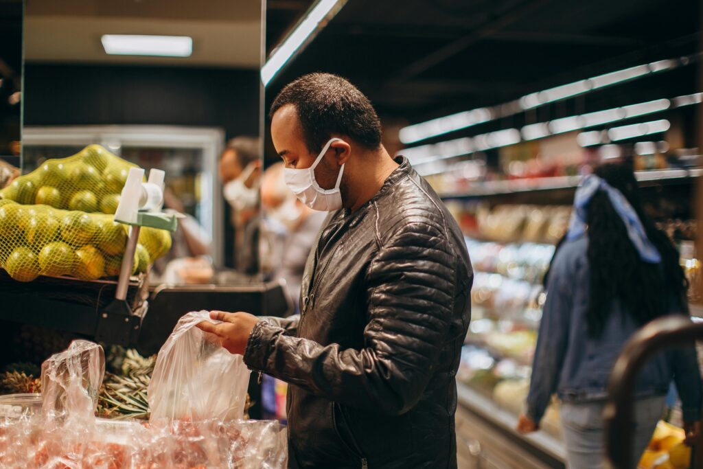 A man wearing a mask shopping for groceries in a supermarket.