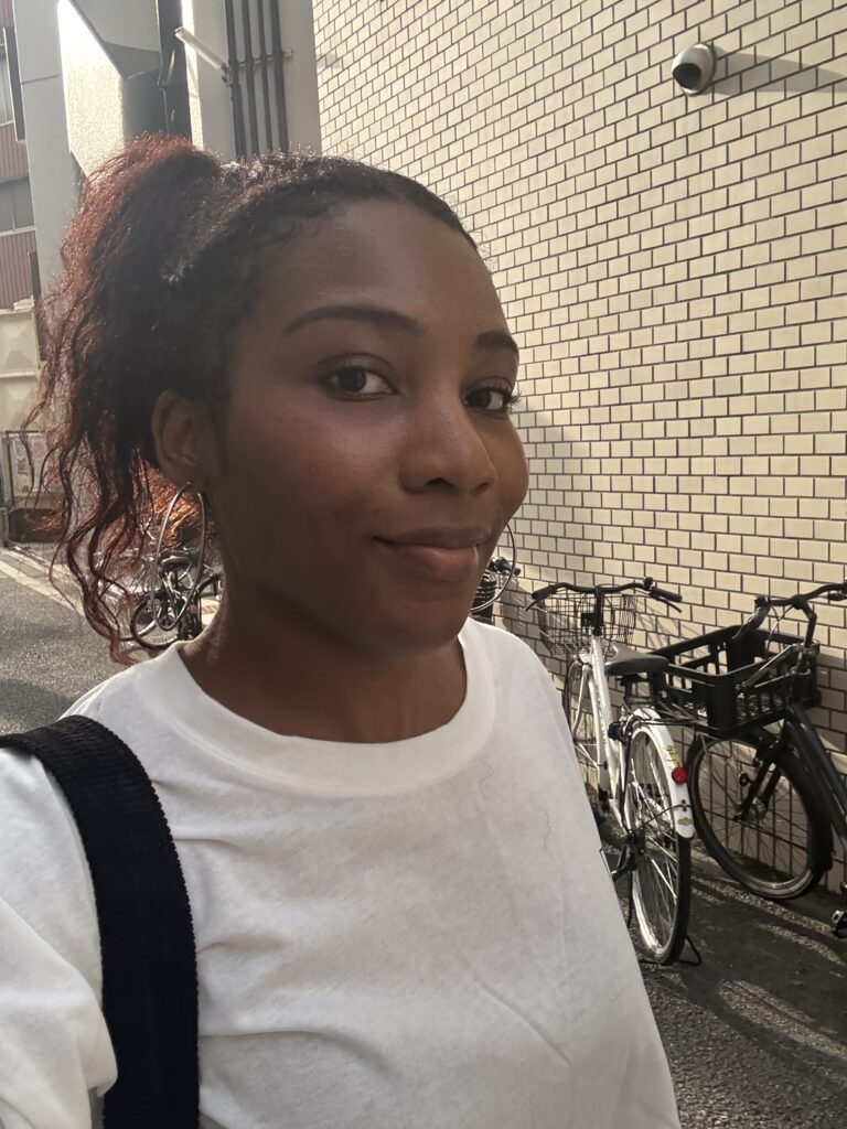 Woman smiling indoors with braided bun hairstyle.
