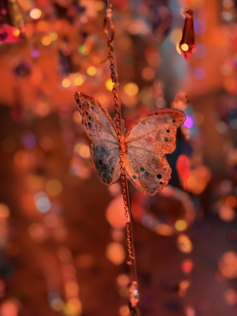 A decorative butterfly ornament hanging among colorful lights and crystal-like decorations.