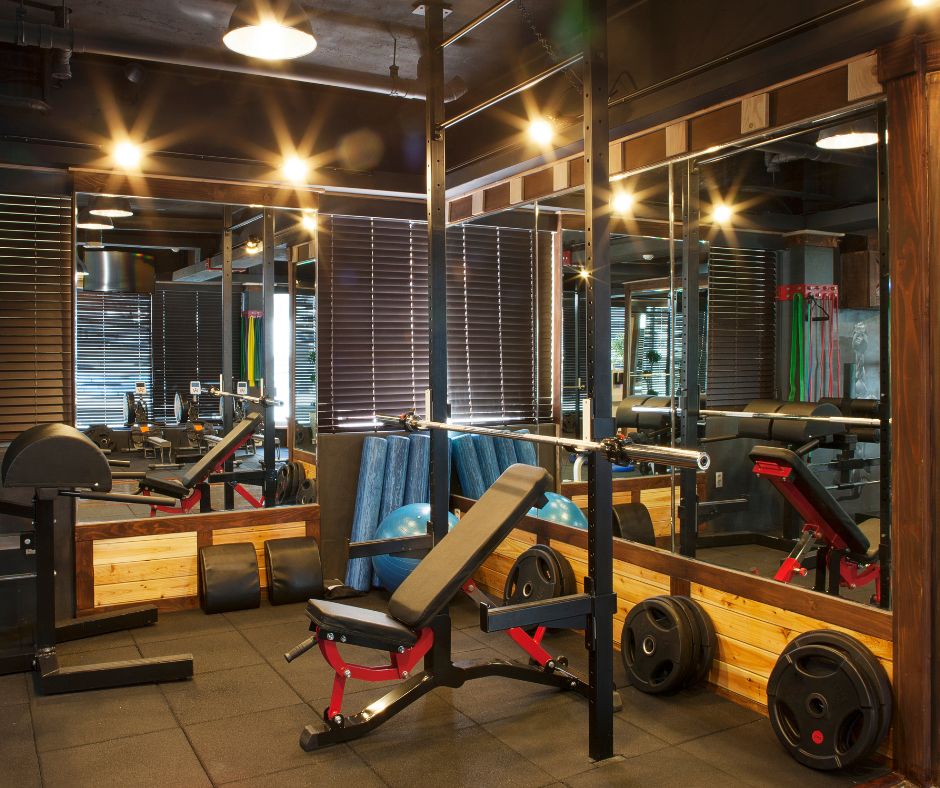 Interior of a Tokyo gym featuring weight benches, barbells, and mirrors under warm lighting.