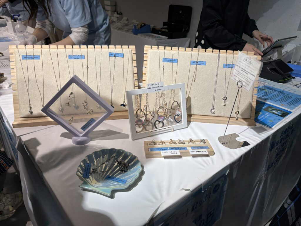 A display table with ocean-themed jewelry including necklaces, rings, and earrings, arranged neatly on stands at a shop counter.