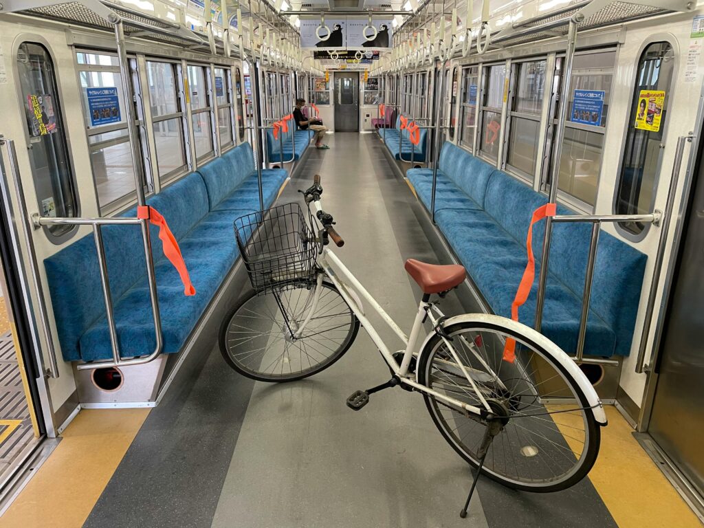 An empty train car with blue seats and a white bicycle placed in the middle of the aisle.