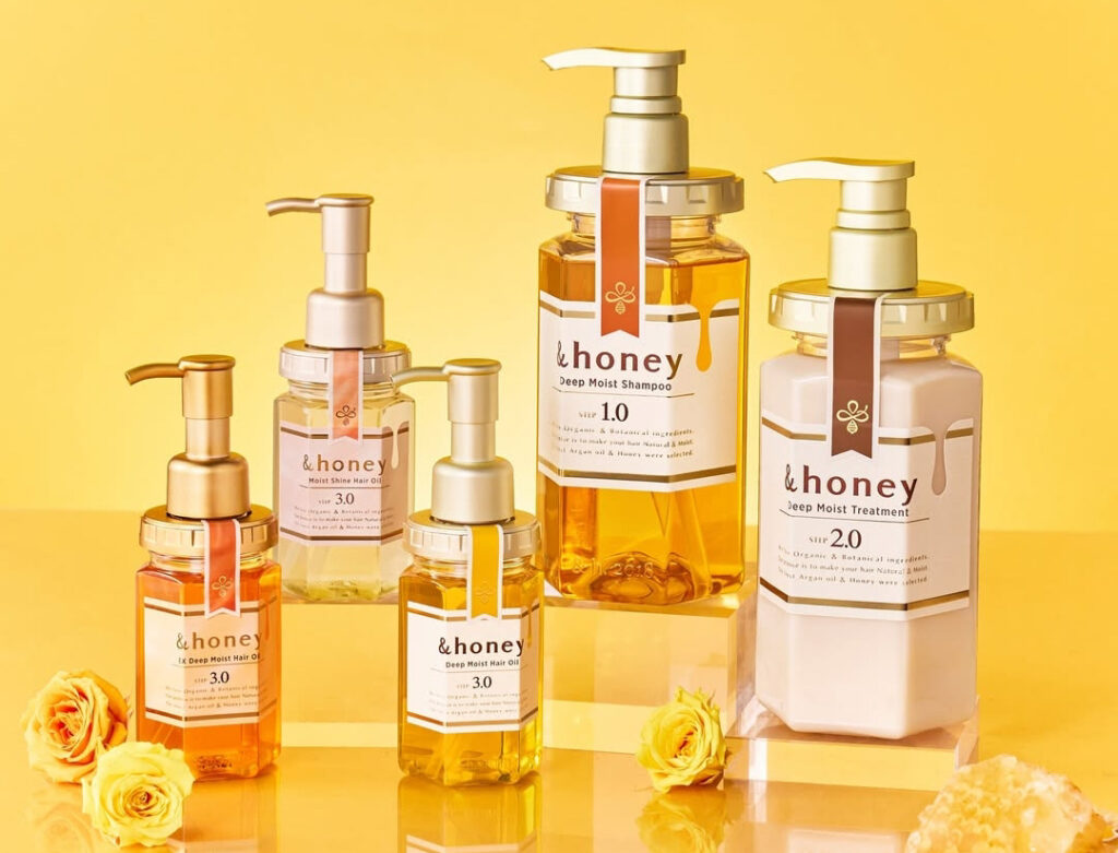 &honey Deep Moist Shampoo, Treatment, and Hair Oil bottles arranged on a yellow background with honey and yellow roses.