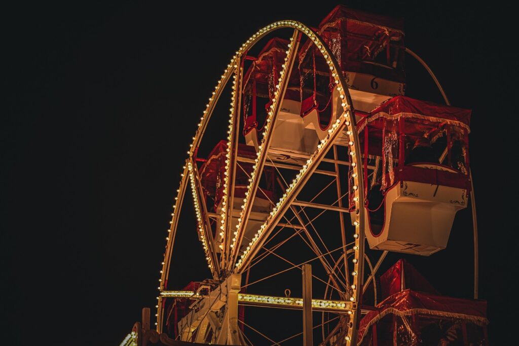 A brightly lit Ferris wheel at night with red and white gondolas decorated in a festive holiday style in Kansai