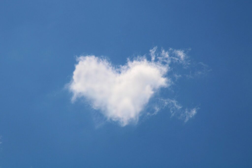 Heart-shaped white cloud floating in a clear blue sky, symbolizing emotional openness and mental well-being.