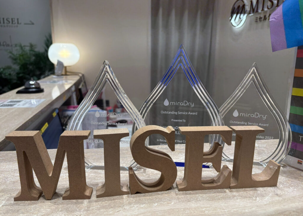 Misel Clinic reception area displaying MiraDry service awards and clinic branding in Japan