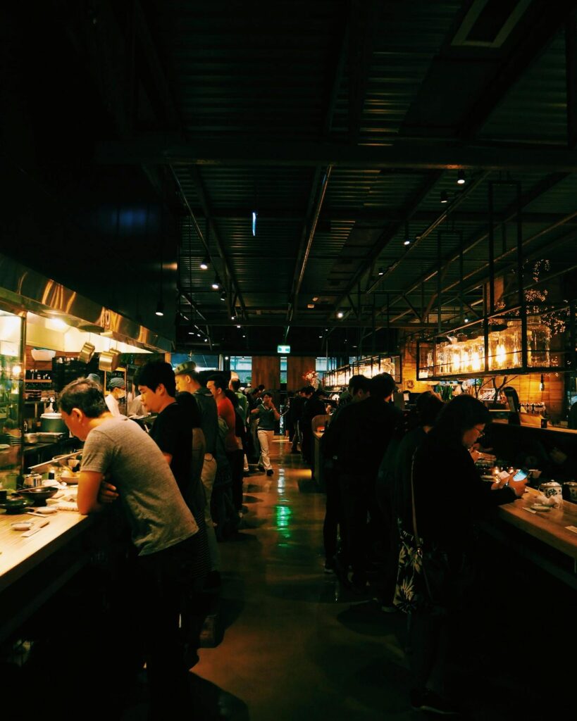 Busy Japanese izakaya with customers standing and eating at a counter