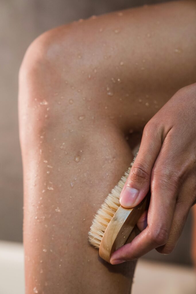 Close-up of someone scrubbing their leg with a bath brush