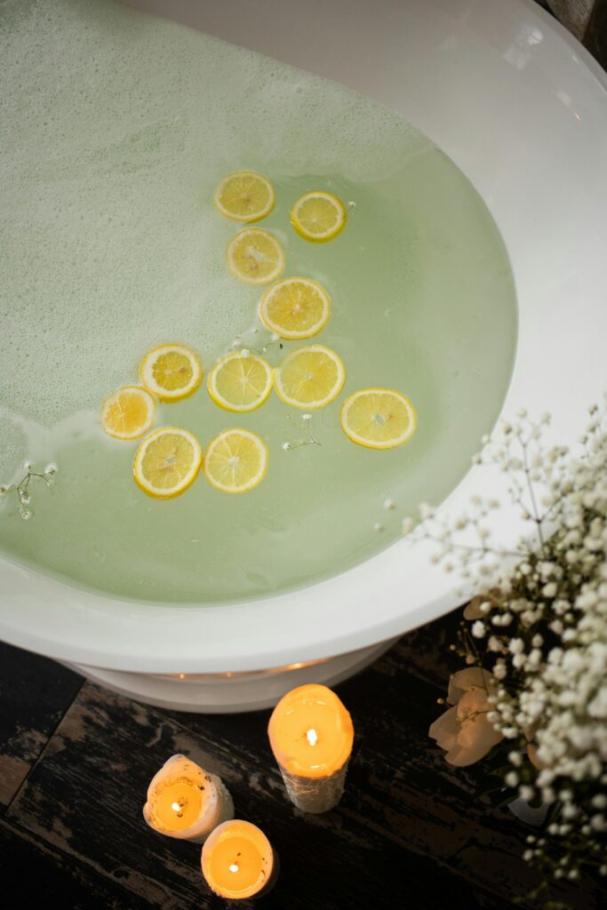 Tub filled with water and lemon slices surrounded by lit candles