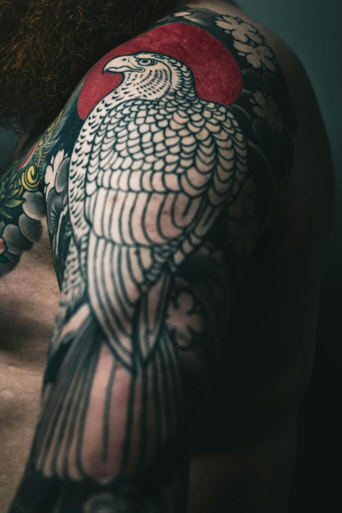 Close-up of a large tattoo featuring a white bird with a red circle behind it