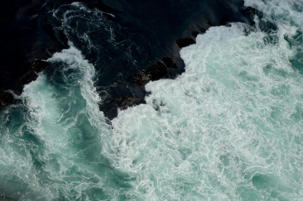 Rough ocean waves crashing with strong white foam and dark water beneath.