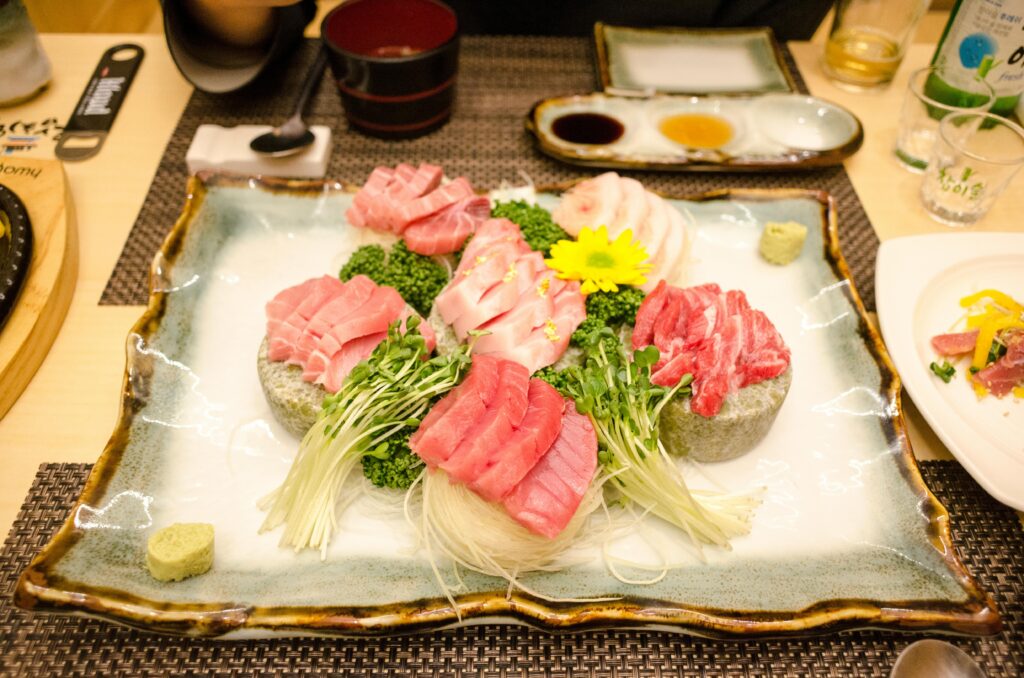 Assorted sashimi slices neatly arranged on a plate with garnishes