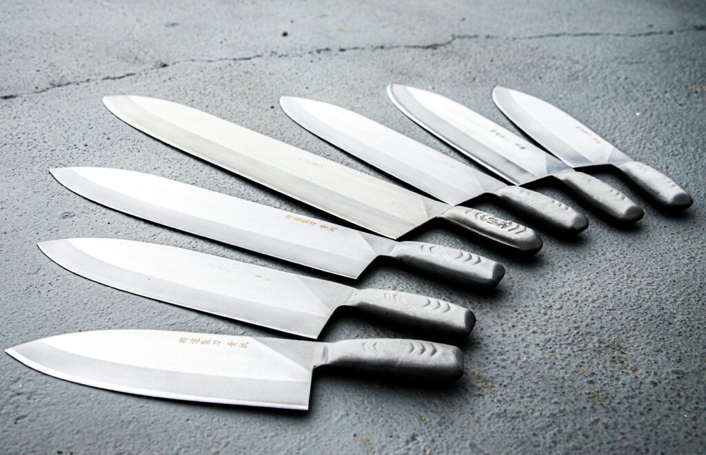 Lineup of traditional Japanese knives arranged on a concrete surface