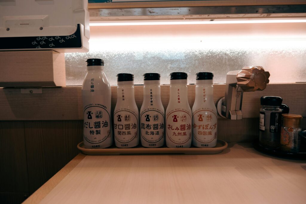 Row of different regional soy sauce bottles lined up on a Japanese restaurant counter