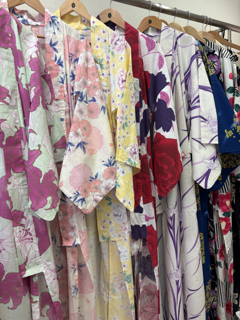 A rack of colorful floral-patterned kimonos neatly hung inside a kimono rental shop in Japan.