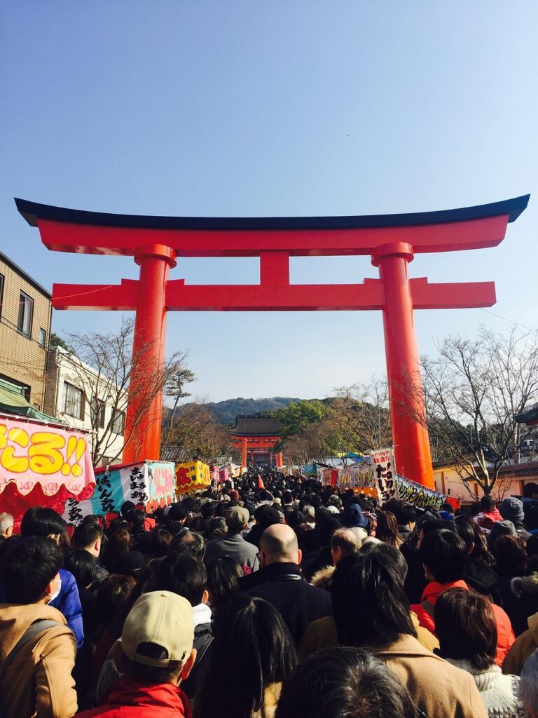 Large crowd passing through a red torii gate during Hatsumode, the first shrine visit of the Japanese New Year.