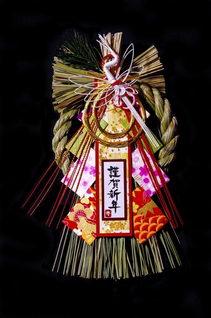 Traditional Japanese shimekazari New Year decoration made of straw, pine, and decorative paper on a black background.