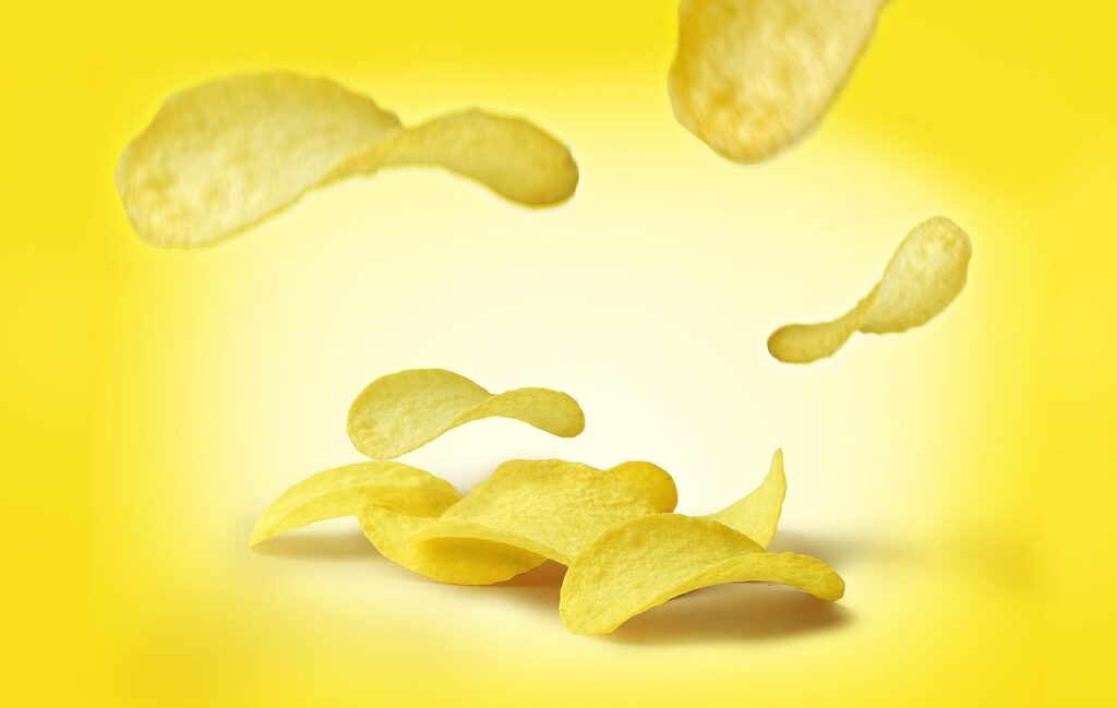 Potato chips floating against a bright yellow background