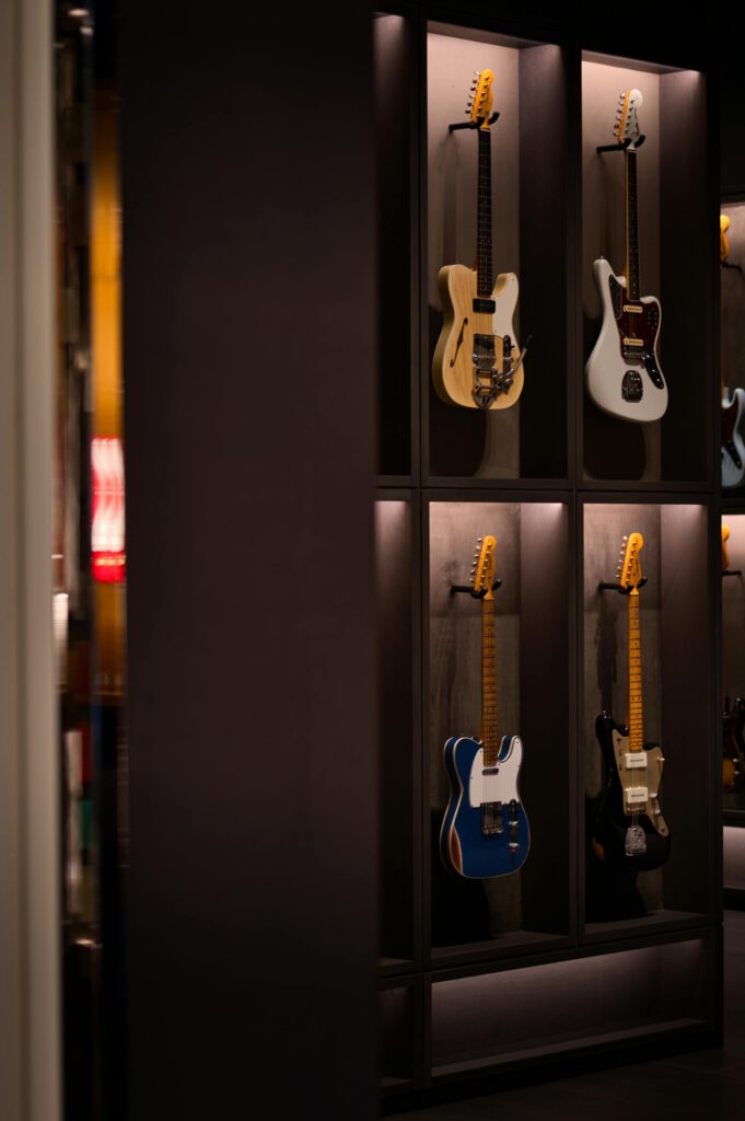 Electric guitars displayed in individual wall-mounted cases inside a modern guitar shop