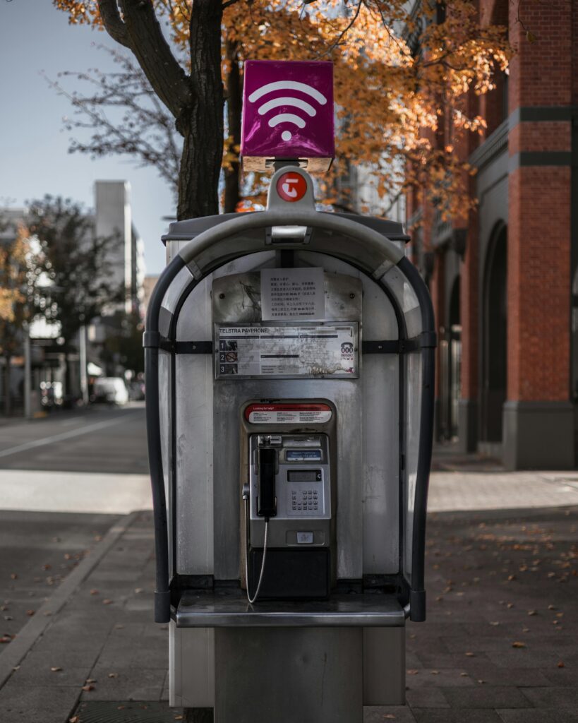 Public Wi-Fi hotspot sign mounted above a street phone booth in an urban area, symbolizing free internet access in cities.