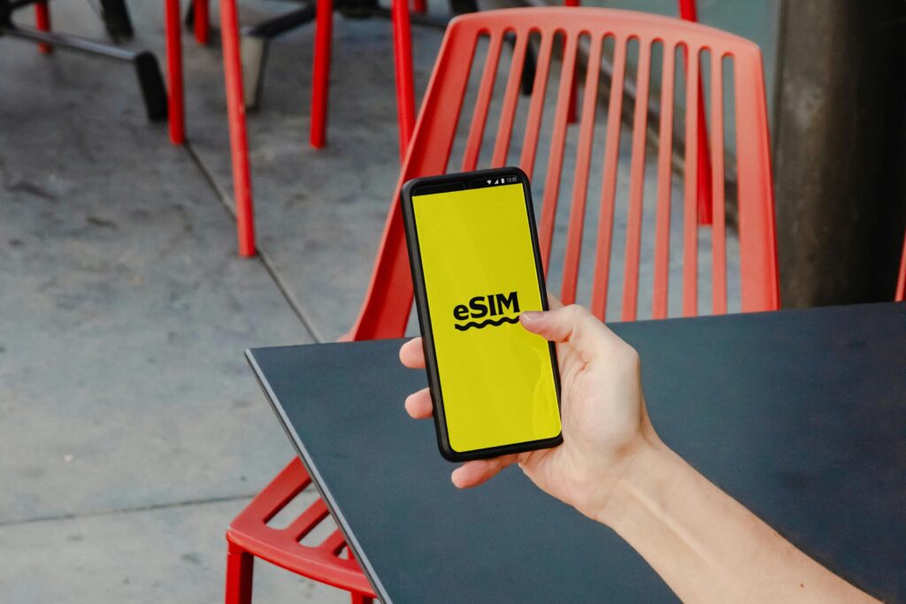 Hand holding a smartphone displaying eSIM activation screen at an outdoor café, representing digital SIM use for internet access in Japan.