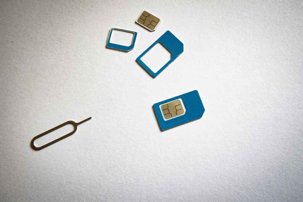 Physical SIM cards with SIM ejector tool on a white surface, illustrating travel SIM card setup for mobile data access.