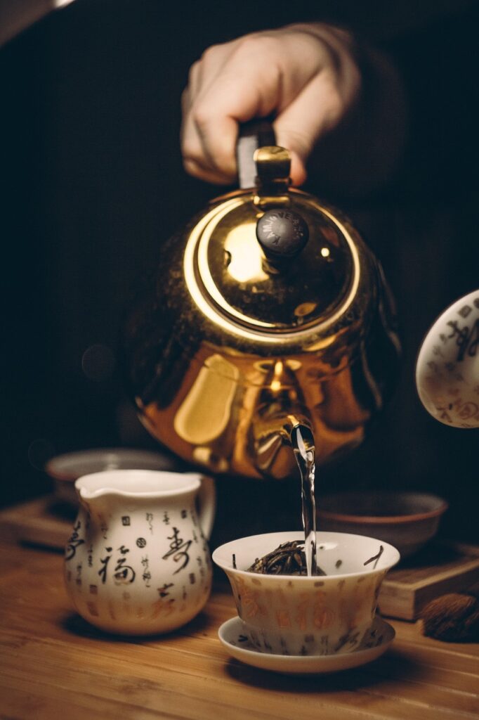 Golden teapot pouring hot tea into a ceramic cup during a traditional Japanese tea moment, evoking calm and craftsmanship.